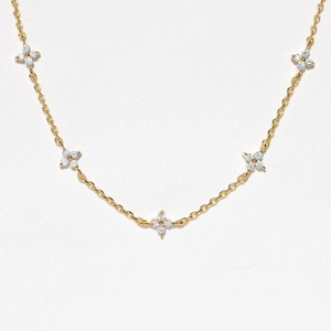 Close-up of golden necklace featuring delicate clover pendants with micro-set zircons