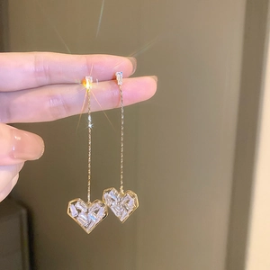 Détail de boucles d'oreilles cœur en or avec zircons blancs scintillants taille baguette