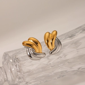 Detail of twisted two-tone gold and silver stainless steel stud earrings on glass
