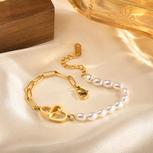 Detailed close-up of 18K gold-plated heart pendant and pearls on elegant satin surface
