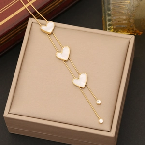 Elegant gold stainless steel necklace with three white shell heart pendants on gift box