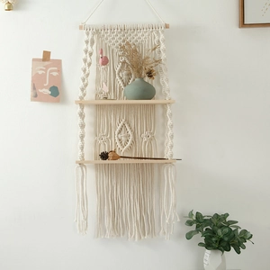 Detail of bohemian hand-woven cotton macrame wall shelf with two-tier wooden planks