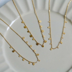 Minimalist gold titanium steel necklaces with geometric discs on a ceramic plate