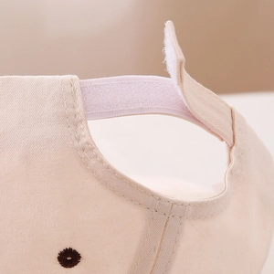 Détail de la sangle velcro et des coutures fines sur une casquette bébé beige