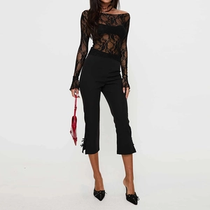 Detail of sheer black lace long sleeve top and flared trousers with bow accents