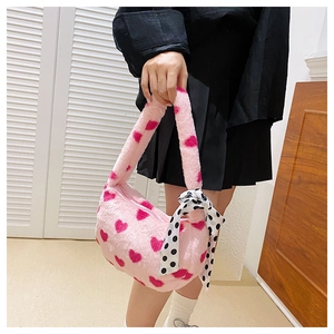 Detail of pink plush handbag with red heart pattern and a black polka dot bow tie