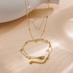 Double-layered gold necklace with white beads and polished spheres in a minimalist design