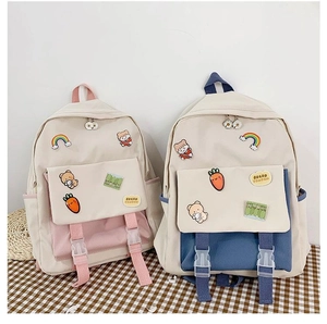 Close-up of dual student backpacks with cute cartoon patches on a checkered cloth