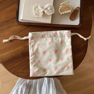 Close-up of floral drawstring storage bag with pink flowers on beige cotton fabric
