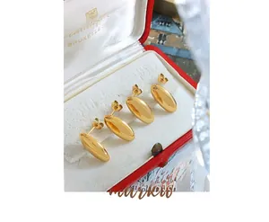 Macro shot of minimalist 18K gold plated bean stud earrings on a vintage red jewelry box