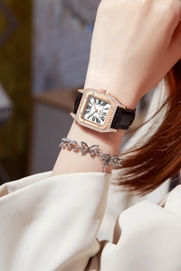 Detailed view of women's square rose gold rhinestone watch with a black leather strap