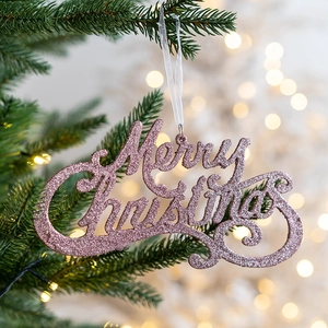 Glittery rose gold Merry Christmas ornament hanging on a festive green pine tree