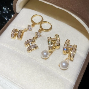 Detail of 14K gold plated H-letter stud earrings with zircon and white round pearls