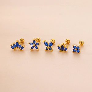 Golden flower and crown stud earrings set with blue zircon on beige background