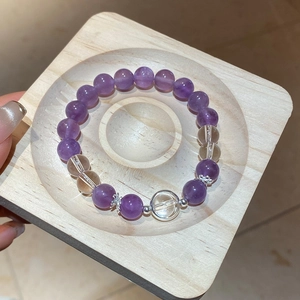 Detailed close-up of natural amethyst beads with silver accents on a wooden display