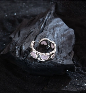 Macro shot of S925 silver open ring with pink enamel hollow hearts on dark rock