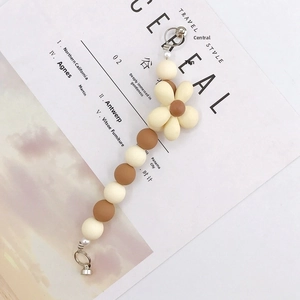 Close-up of cream and brown beaded strap with acrylic flower charm on a magazine page