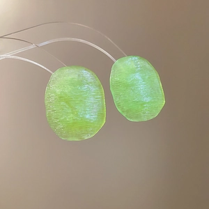 Detail view of green translucent resin earrings showing horizontal brushed texture