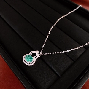 Macro detail of silver gourd necklace pendant with green gemstone and sparkling zircon