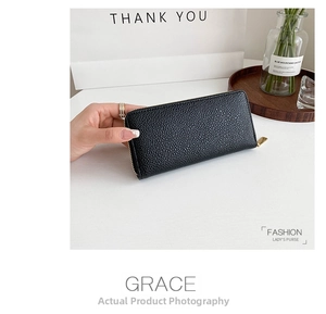 Detail of minimalist black pebbled leather long wallet with a golden zipper closure
