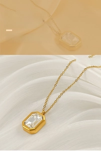 Macro detail of a gold rectangular zircon pendant necklace on white satin fabric