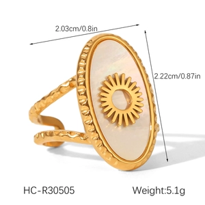 Detail view of a gold sun ring with white shell inlay featuring a textured double band
