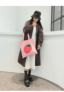 Detail of pink canvas tote bag featuring a cute plush strawberry embroidery patch