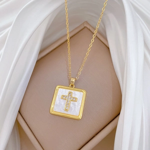 Detail of gold square pendant with white shell and crystal cross on silk padding