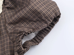 Detail of the elastic waistband on a plaid dress featuring brown checkered fabric texture