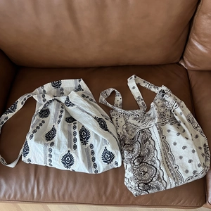 Detail of ethnic striped and paisley print linen tote bags on a leather surface