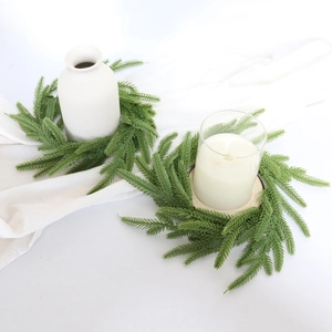 Detail of green PE Norfolk pine needle candle rings on white fabric for home decor