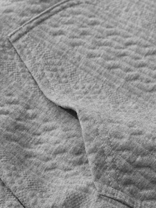 Macro shot of gray jacquard knit fabric showing quilted texture and precise pocket stitching