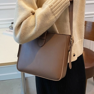 Brown vintage style leather crossbody bucket bag shown on model with adjustable strap