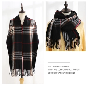 Close-up of warm classic plaid scarf with tassels in black, white, and dark red colors