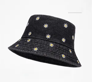 Close-up of white daisy embroidery on dark denim bucket hat with detailed stitching