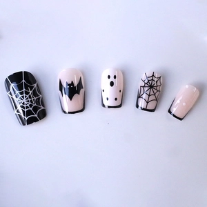 Halloween press-on nails with black bat, white ghost, and spider web nail art designs