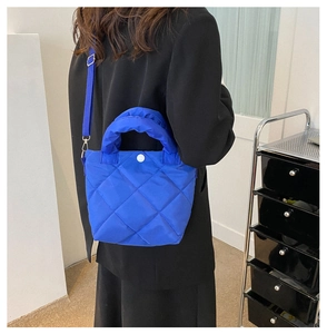 Klein blue quilted oxford fabric handbag with large diamond stitching worn by a model