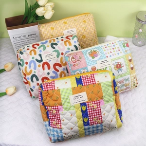 Detailed view of four colorful quilted cotton makeup bags with floral and plaid patterns