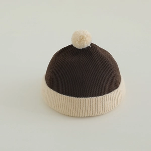 Detail of ribbed knit brown and beige kids docker hat with fluffy pompom decoration
