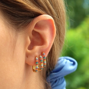 Close-up of 18K gold hoop earrings set with a rainbow of colorful zircon stones