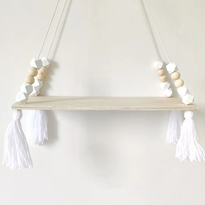 Macro detail of wooden swing shelf featuring white tassels and Nordic geometric beads
