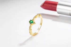 Macro shot of 14k gold ring featuring a central emerald stone and vintage floral band