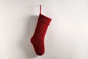 Detail of a dark red knitted Christmas stocking with classic cable stitch pattern