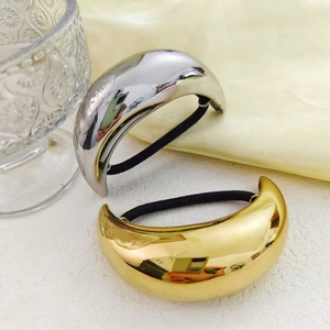 Minimalist gold and silver curved stainless steel hair ties on a white textured surface
