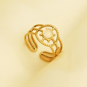 Macro shot of gold stainless steel ring with white gemstone and detailed openwork band