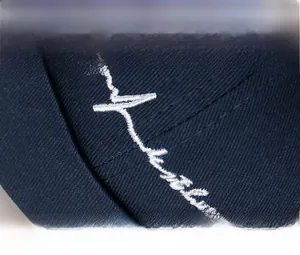 Gros plan détaillé de la broderie blanche sur le bonnet docker en coton bleu marine