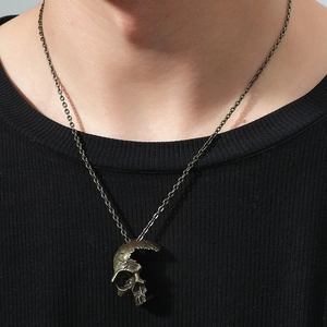 Close-up of gothic bronze skull pendant necklace on black shirt for a vintage male look