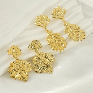 Macro shot of gold-plated titanium steel earrings with abstract coral and hammered textures