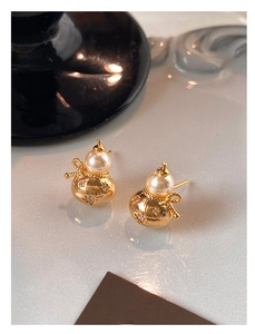 Gros plan d'une boucle d'oreille en perle dorée avec détails en zircon et texture