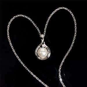 Baroque style necklace with white pearl pendant arranged in heart shape on black background
